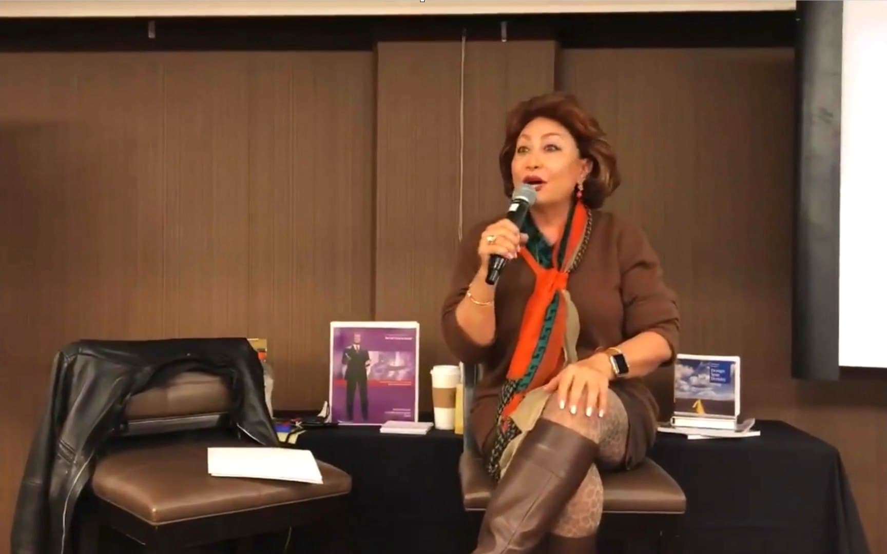 A certified practitioner holding a room, microphone in hand, presenting to an audience